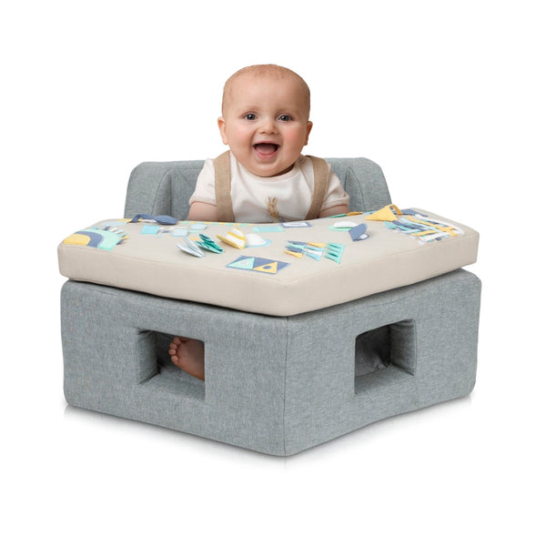 Baby sitting on a gray and beige activity center with a smiling expression.